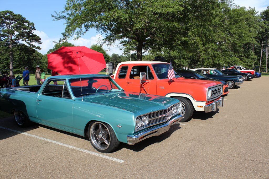 A classic red truck beside a teal classic muscle car.